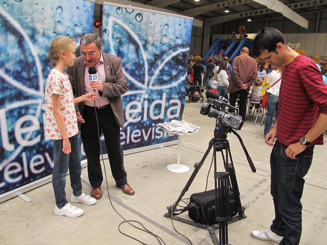 Foto 4. L'alcalde, entrevistat per una noia reportera, al plató que Lleida TV ha instal·lat al pavelló per als nens i nenes